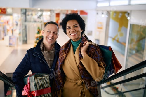Preview: Happy multiracial couple buying Christmas presents in shopping mall.
