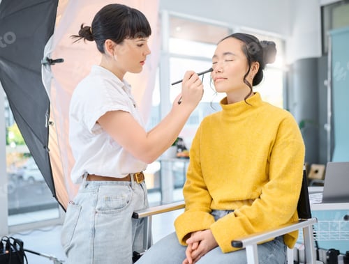 Preview: Beauty, makeup artist and model doing makeup on a for a creative photoshoot in a studio. Cosmetics,