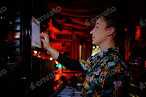 Preview: Woman using touch screen computer while working behind the counter in a bar or pub.