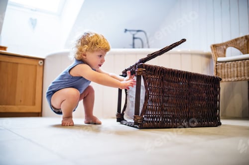 Preview: Toddler boy with a laundry basket in the bathroom.