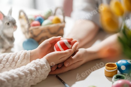 Preview: Close Up of Family Hands Holding Painted Easter Egg in Bright Spring Setting