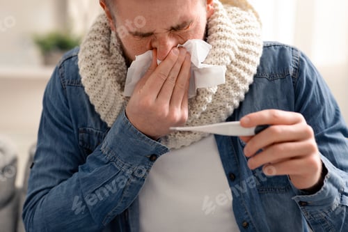 Preview: Sick man checking his body temperature and blowing nose
