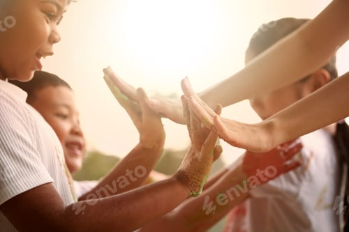Preview: Happy children giving high five after a kid's plays outside in the evening.