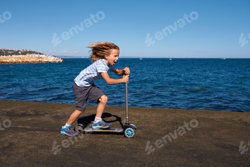 Preview: Boy riding a scooter on a pier at sunny day