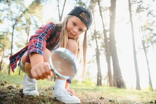 Preview: Image of cute kid with magnifying glass exploring the nature outdoors.