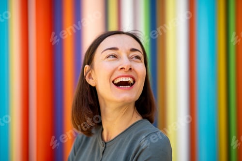 Preview: Close up middle age woman laughing against colorful background