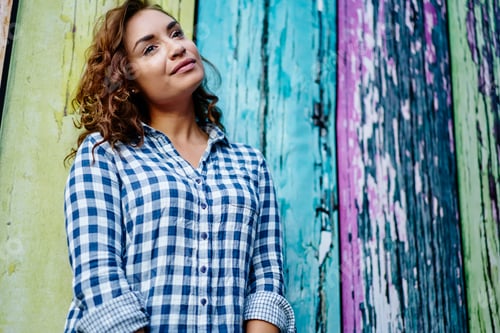 Preview: Woman Wearing Plaid Shirt Leaning Against Painted Wall