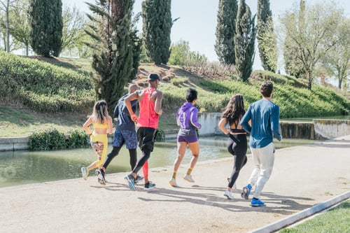 Preview: Group of runners training in a park. Rear view, back to camera. Happy and smiling.