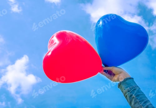 Preview: the girl is holding balloons in the form of a heart of red and blue,