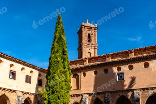 Preview: Monasterio de Piedra architecture with tall cypress tree under a blue sky