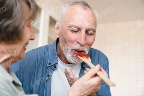Preview: Cropped image senior old wife treating husband with souse while cooking, preparing food meal dinner