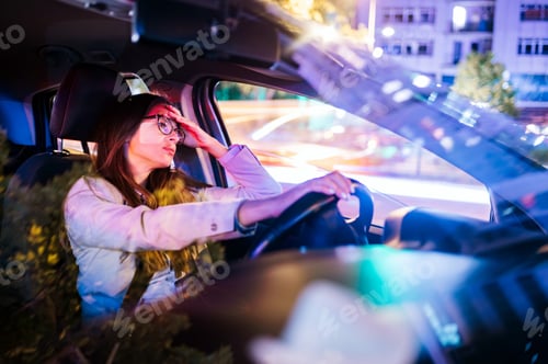 Preview: Business woman driving a car in a city during a night
