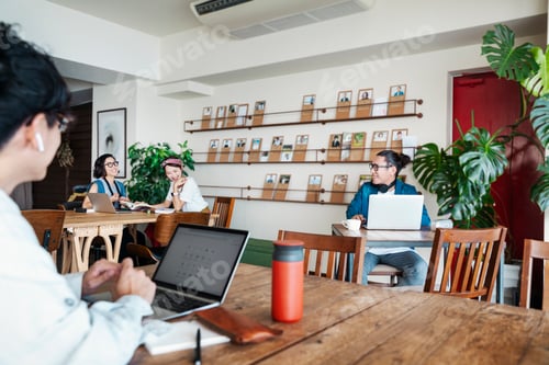 Preview: Group of young Japanese professionals working on laptop computers in a co-working space.