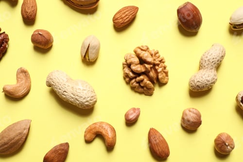 Preview: Different delicious nuts on yellow background, flat lay