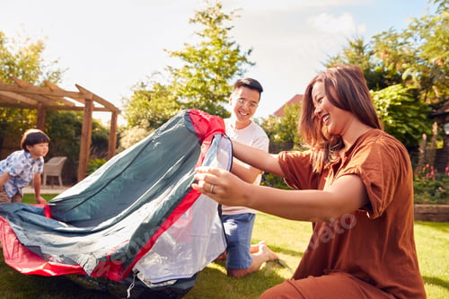 Preview: Asian Family In Garden At Home Putting Up Tent For Camping Trip Together