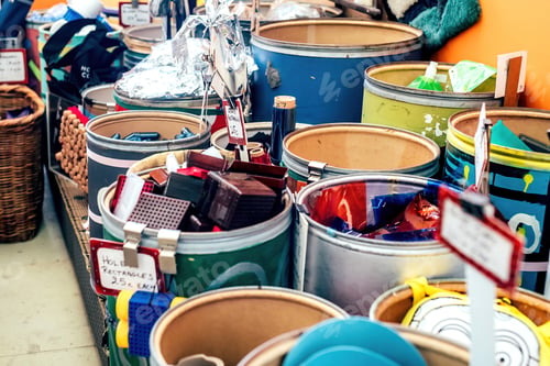 Preview: Big barrels with different recycling materials in a shop. Blurred image with selective focus.