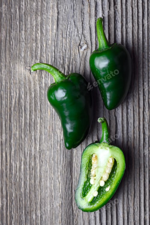Preview: Three green mexican jalapeno hot peppers on rustic wooden table