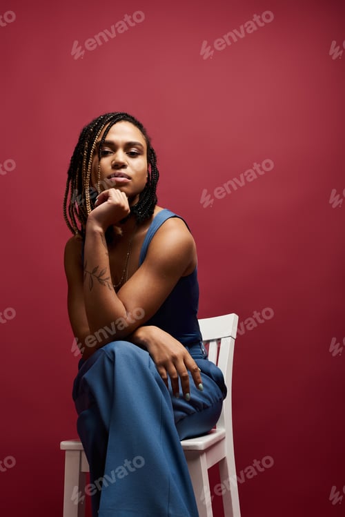 Preview: Stylish young African American woman with braids posing confidently in a studio setting