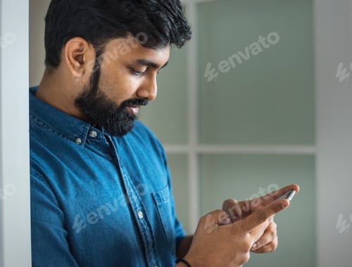 Man Using Cell Phone Indoors by the Window