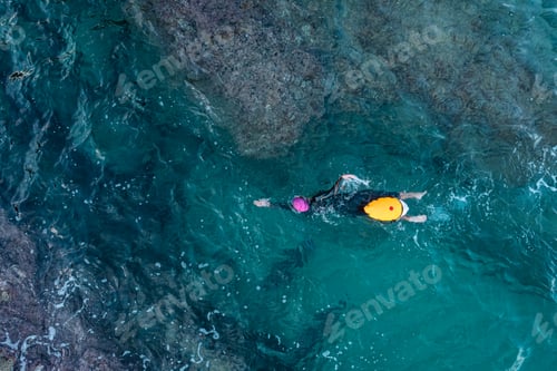 Preview: Aerial top view from drone of a swimmer in open water with wetsuit and buoy