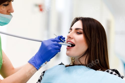 Preview: Dentist doctor drills teeth with a drill to a young woman. Girl at the dentist's appointment