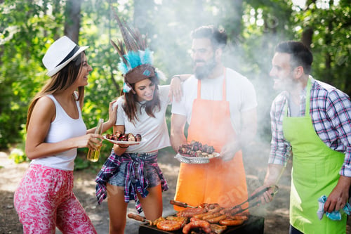 Preview: Group of happy friends eating and drinking beers at barbecue dinner