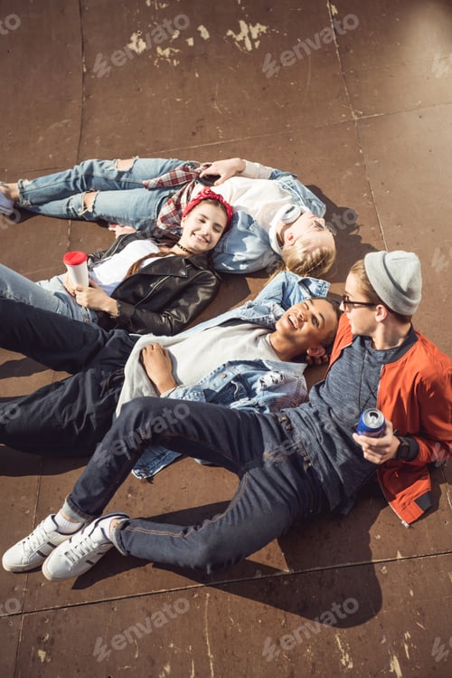 Preview: High angle view of teenagers group lying together and resting at skateboard park