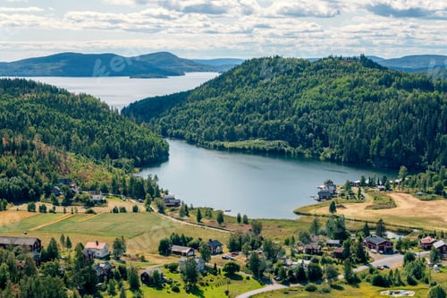 Preview: High angle shot of rural houses on a shore of a lake surrounded by green hills