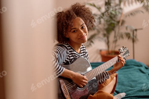 Preview: Female musician guitarist playing guitar at home