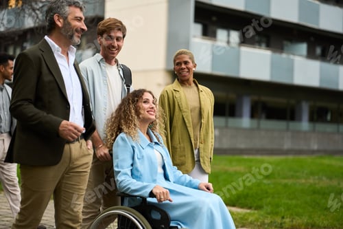 Preview: Diverse business team with woman in wheelchair walking outdoors