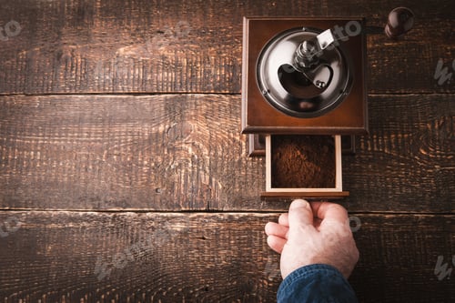 Preview: Coffee mill with hand on the wooden table horizontal