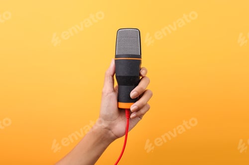 Preview: Hand Holding Microphone For Audio Recording Isolated On Yellow Background