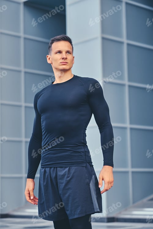 Preview: A man in a black sportswear over modern building background.