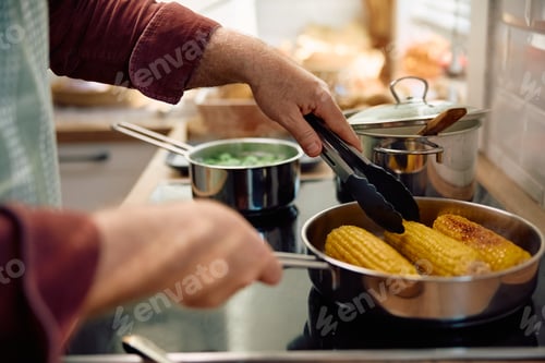 Preview: Close up of man preparing corn while cooking for Thanksgiving in the kitchen.