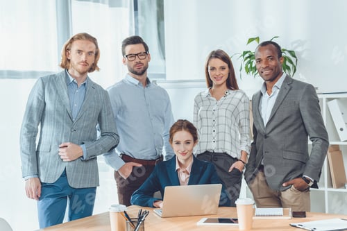Preview: business team standing against sitting woman at office space