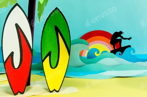 Preview: Creative paper craft of a surfer on the waves and two surfboards on a sandy beach