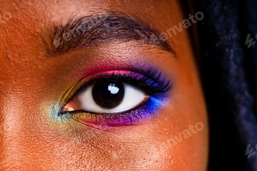 Preview: Female with rainbow make-up and long eyelashes in blue studio baclground