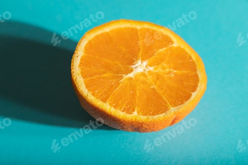 Preview: Ripe cut orange on blue pastel background. Side view, close up, hard light.
