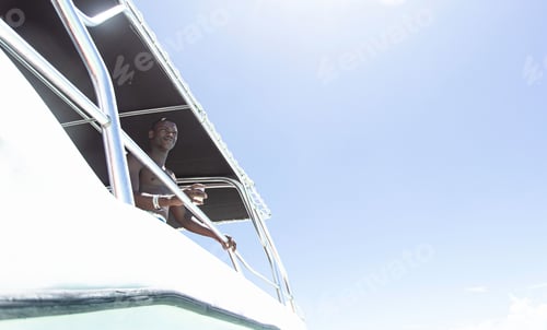 Preview: Shirtless black man holding drink on yacht