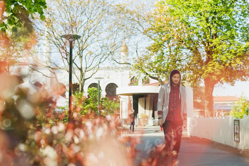 Preview: Man looking away while walking on footpath outside building