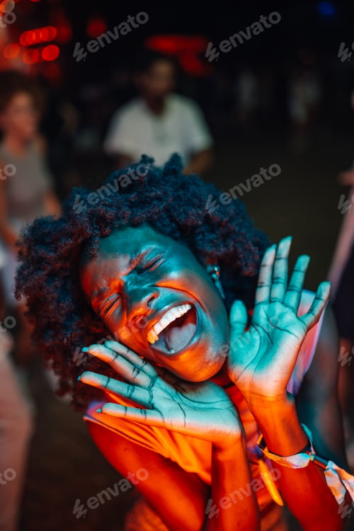 Preview: Enthusiastic young woman dancing and enjoying live music at night concert