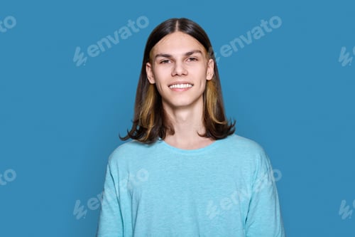 Preview: Headshot portrait of teenage guy looking at camera on blue background