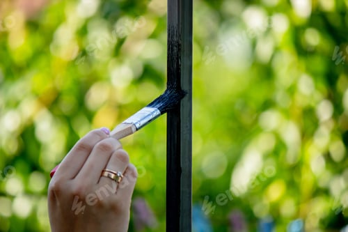 Preview: close up of painting metal with brush in garden.