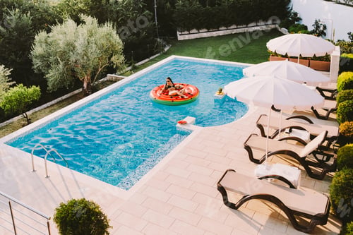 Preview: Sexy woman relax in swimming pool laying on inflatable watermelon pool toy on summer vacations