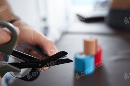 Preview: Adult man cutting color tape, colored ribbons on the table
