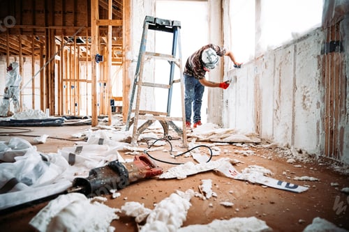Preview: Construction worker removing spray foam on the walls of a building