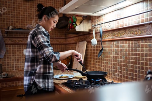 Preview: Ethnic woman cooking delicious breakfast in kitchen