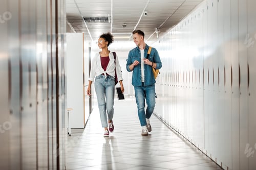 Preview: full length view of two multiethnic students in corridor in university