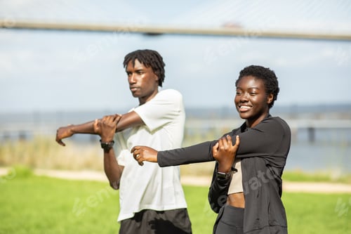 Preview: Young adults stretching outdoors near a bridge during a sunny day