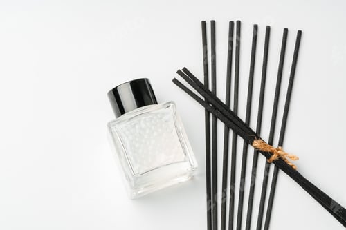 Preview: A minimalist display of essential oil and black diffuser sticks on a clean white background